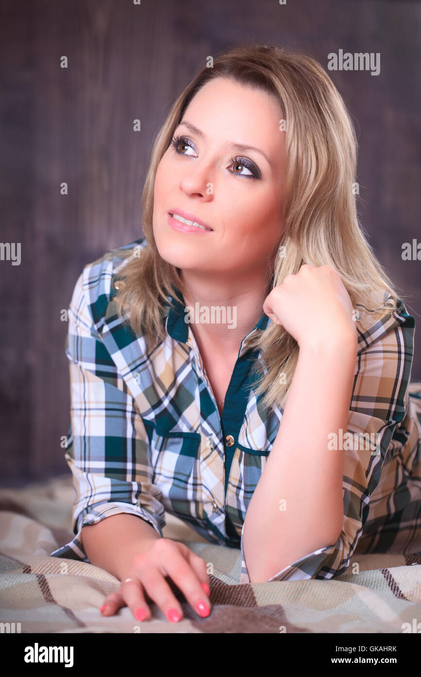 Ritratto di una giovane donna attraente giacente su un plaid Coperte, close-up verticale, riprese in studio Foto Stock