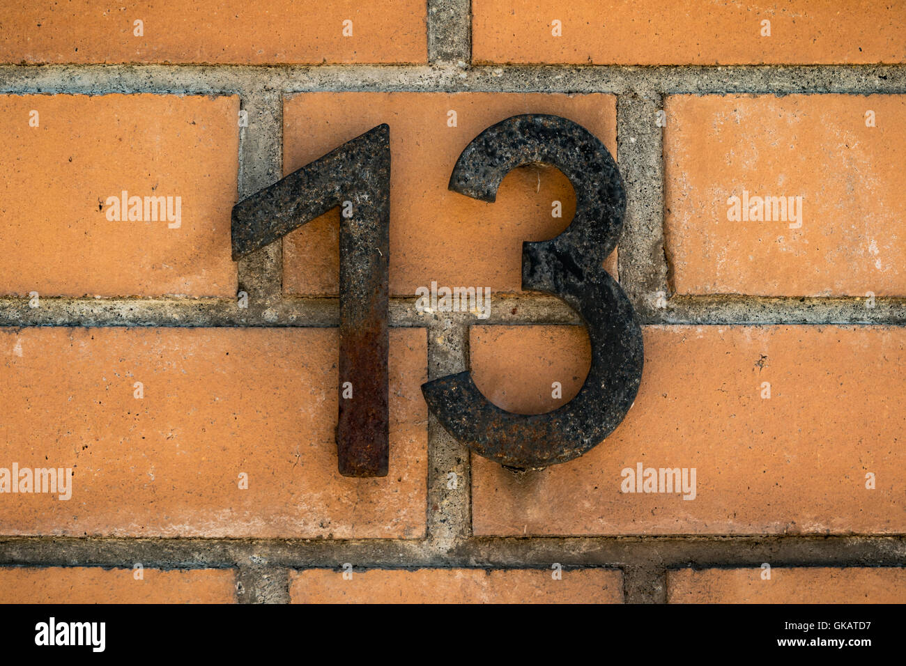 Numero 13 su una parete arancione Foto Stock