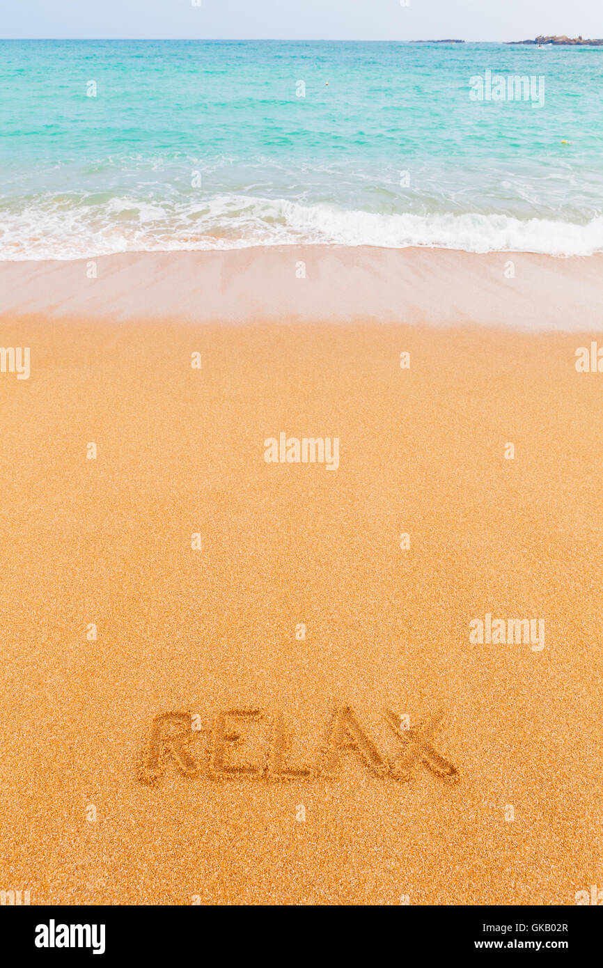 Bellissima spiaggia naturale dal blu del mare con iscrizione 'relax' fatta sulla sabbia Foto Stock