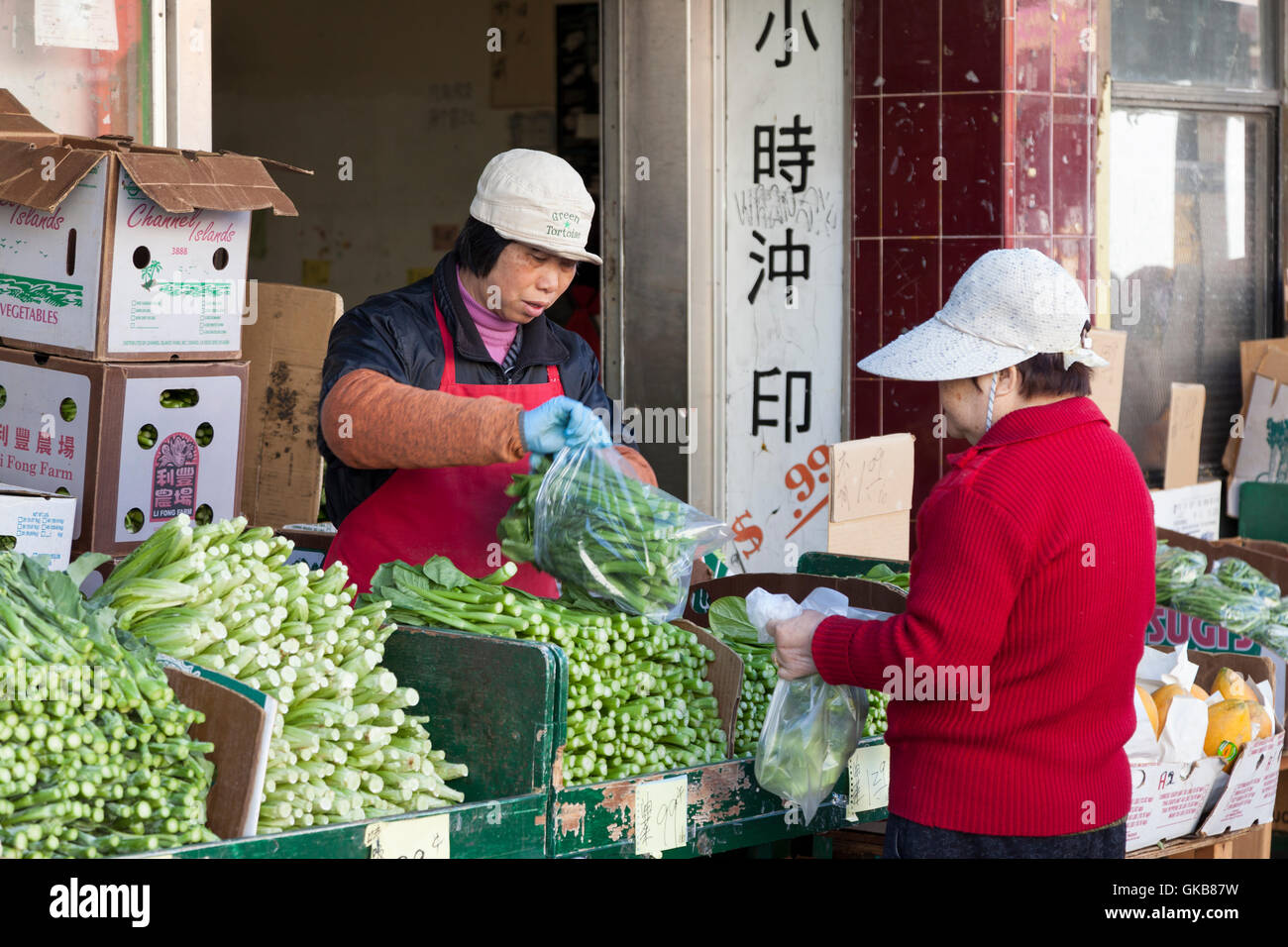 San Francisco, California: negoziante vendere gai lan (broccoli cinesi) per un cliente lungo Stockton Street. Foto Stock