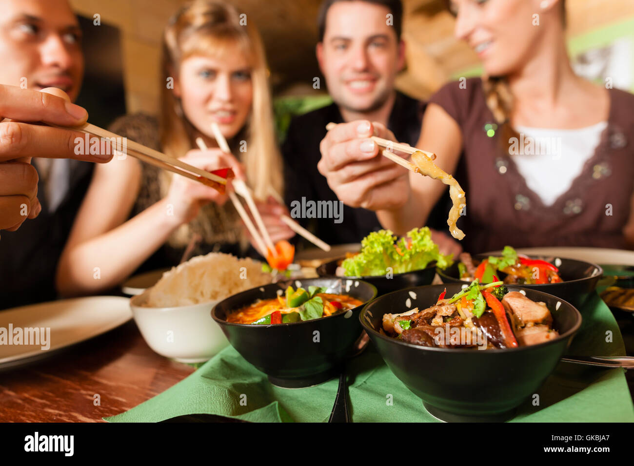 I giovani di mangiare in un ristorante thai,mangiare con bacchette,close up su mani e cibo Foto Stock