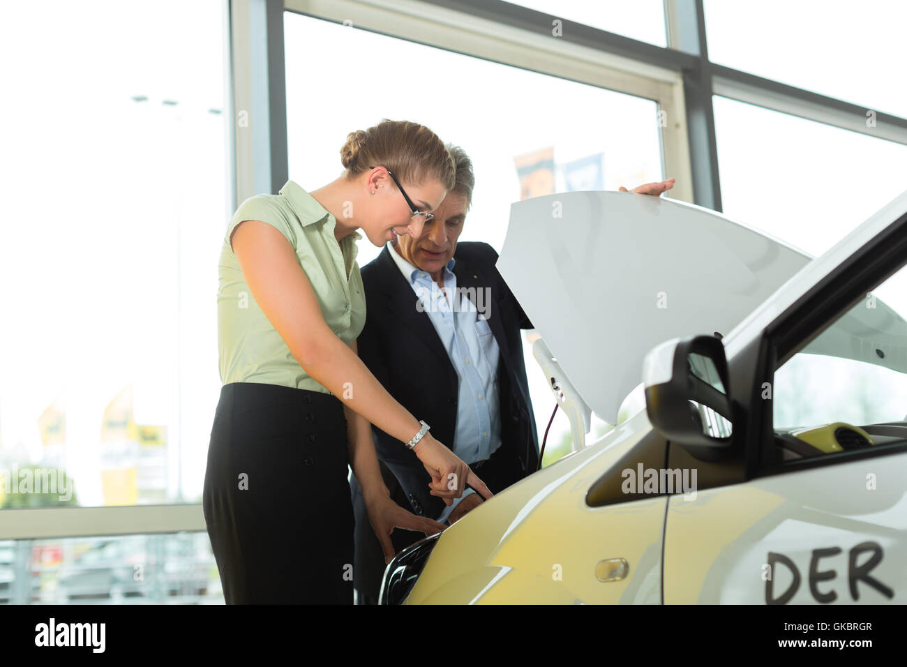 Concessionari e donna in concessionaria guardando sotto il cofano per auto Foto Stock