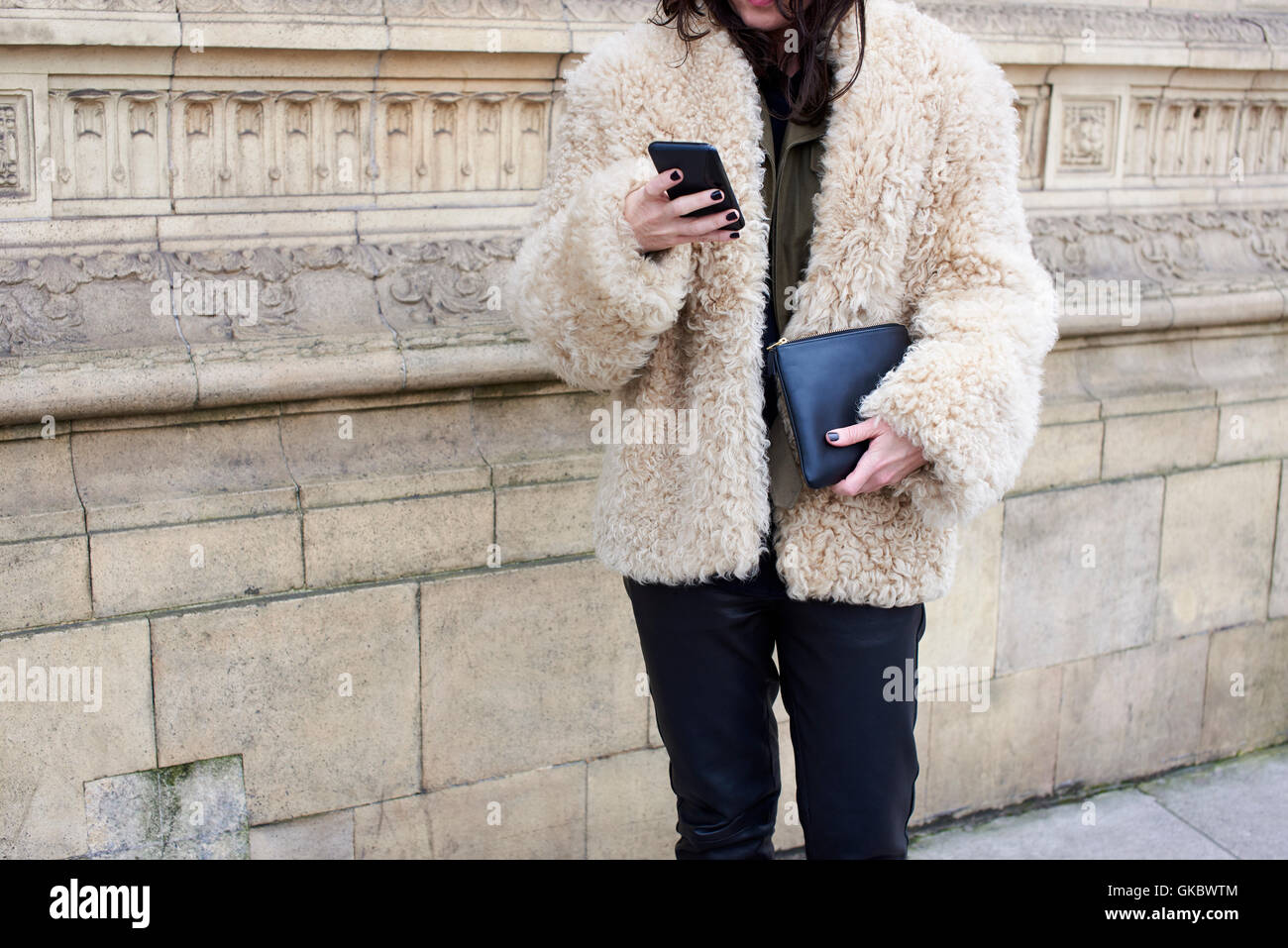 Donna che indossa giacca di pelle di pecora utilizza lo smartphone, il  raccolto Foto stock - Alamy