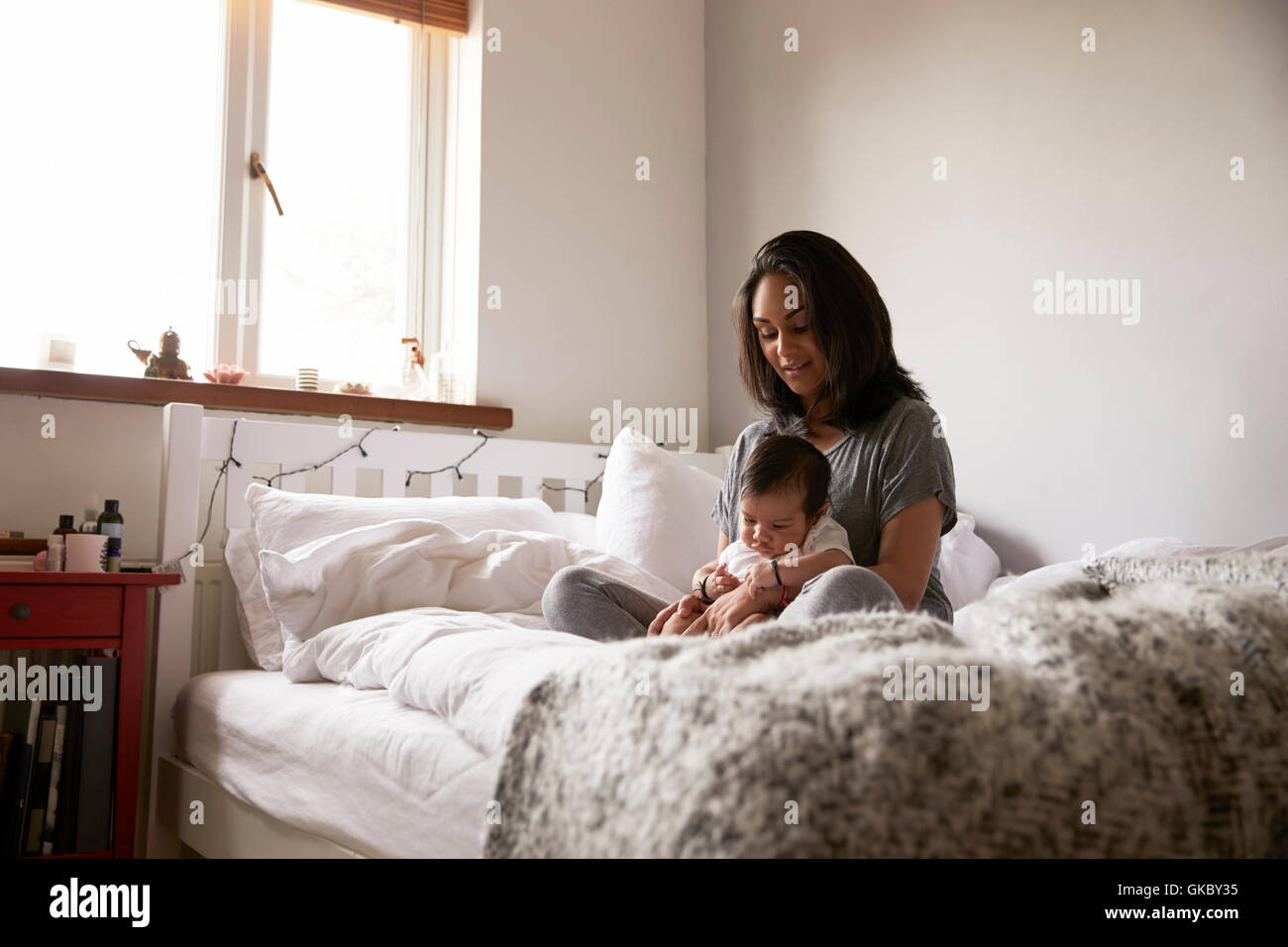 Madre seduta sul letto con baby boy Foto Stock