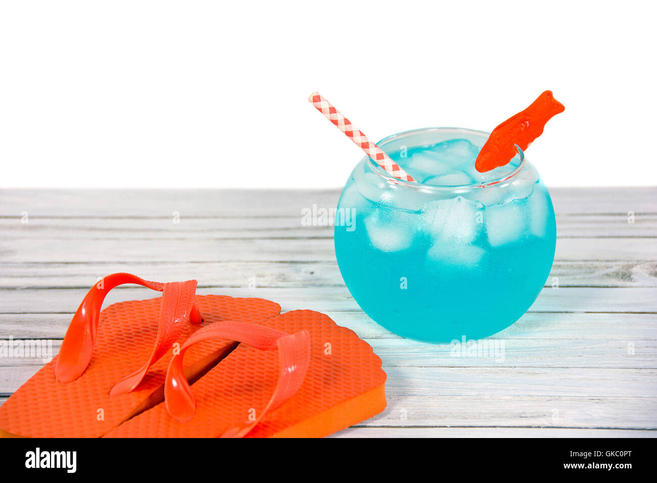 Estate arancione flip-flop e fish bowl drink in legno dipinto di bianco. Foto Stock