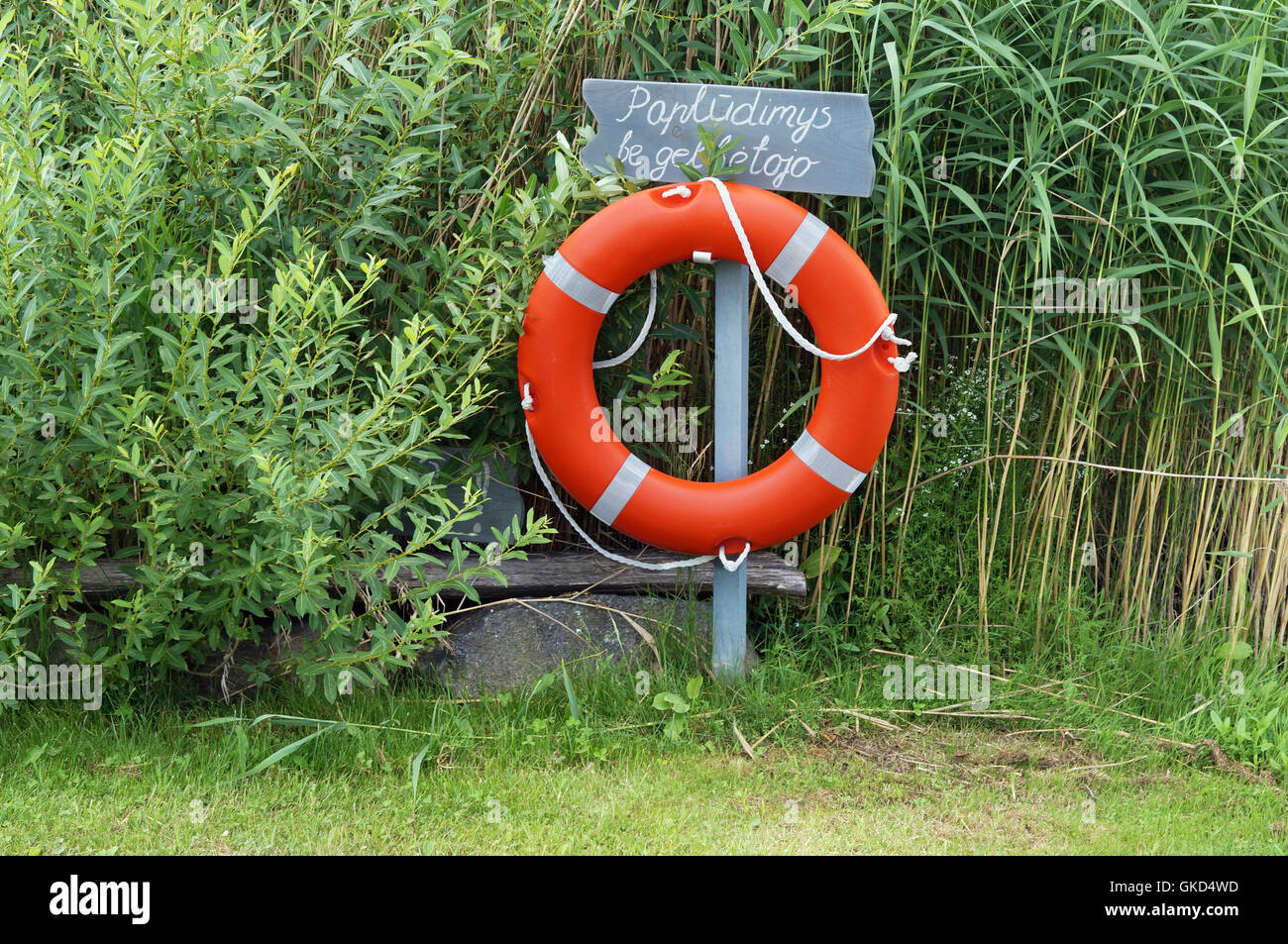 La ciambella rossa si blocca su un braccio metallico. Una scritta a mano in lingua lituana - la spiaggia senza i soccorritori. Standard Foto Stock