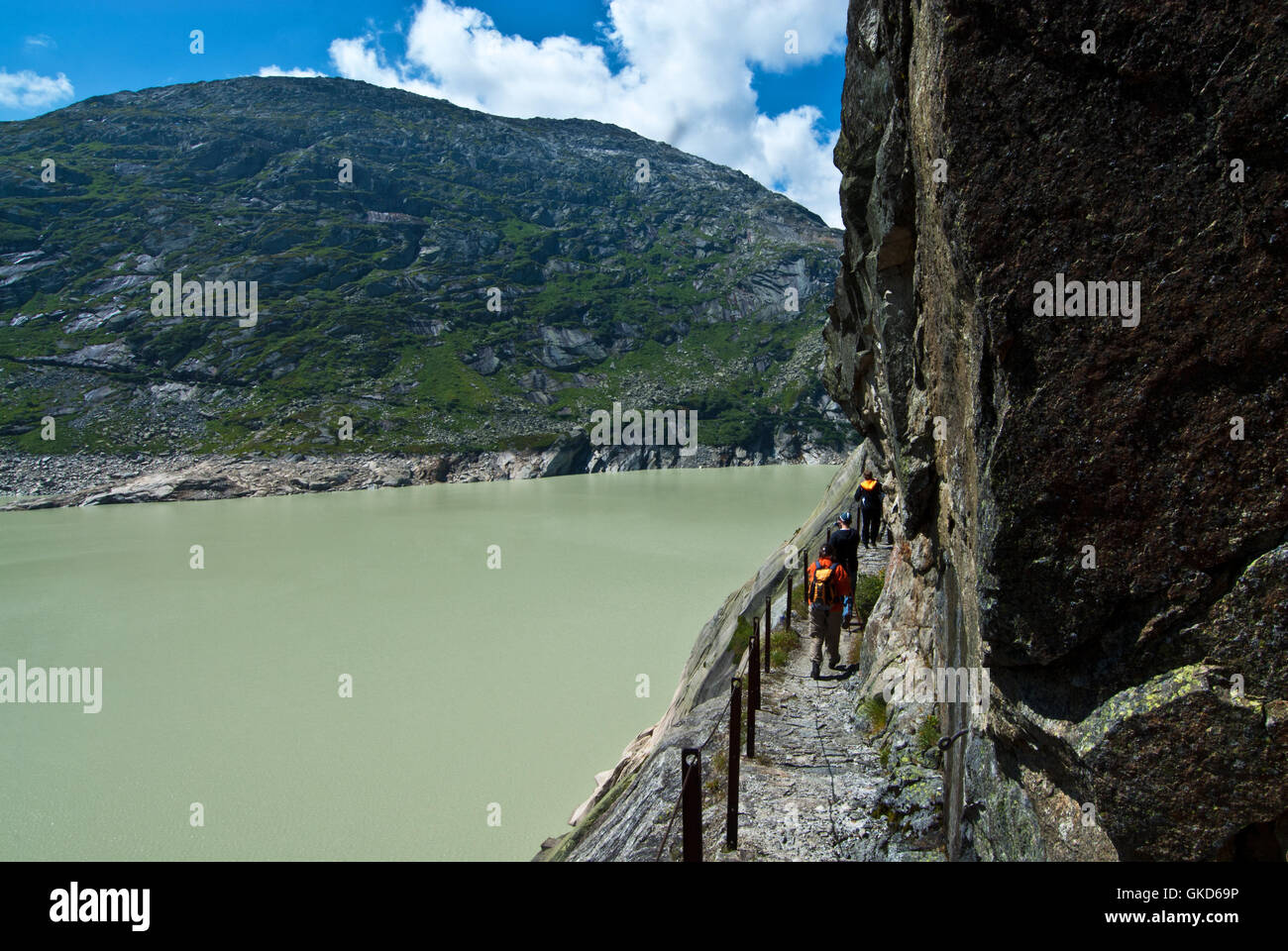 Gli escursionisti sul sentiero intagliato nella roccia di granito Lauteraar lungo lago, Grimsel, Alpi bernesi. Svizzera Foto Stock
