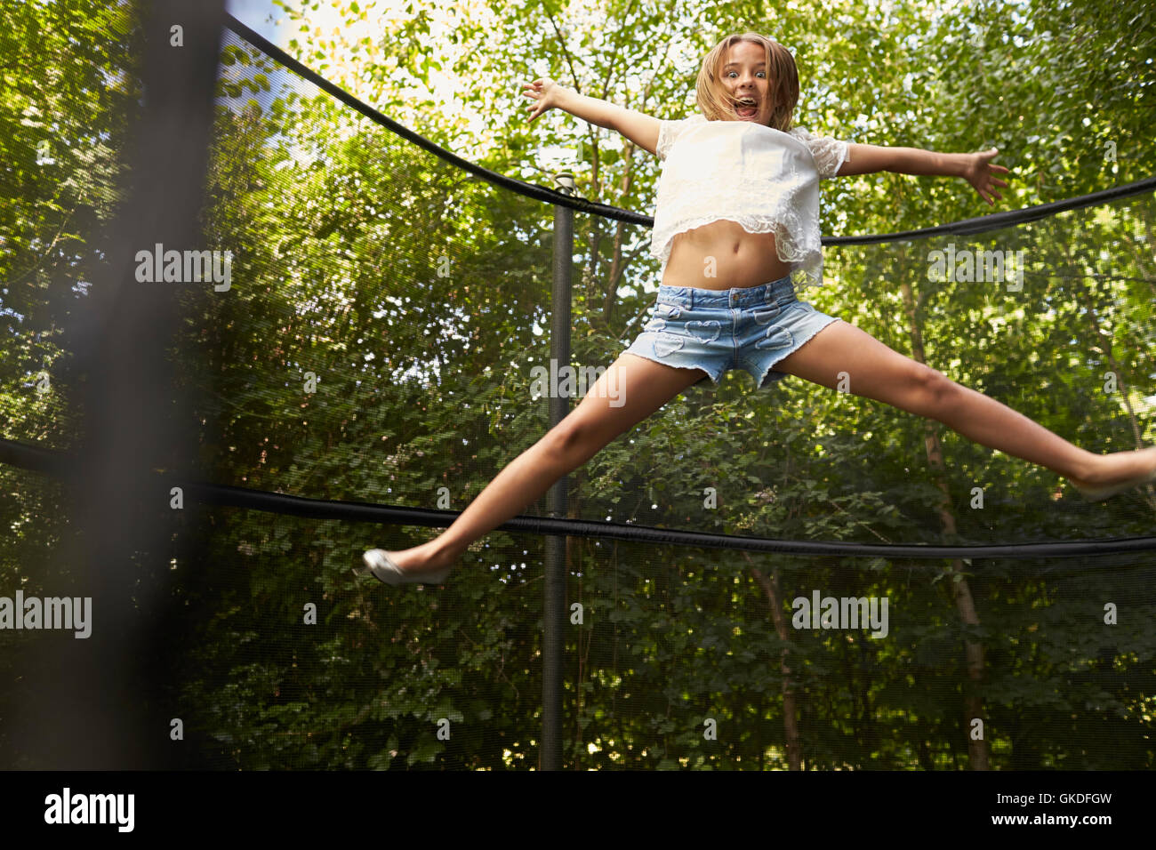 Ragazza stella fa saltare sul trampolino in un giardino Foto Stock