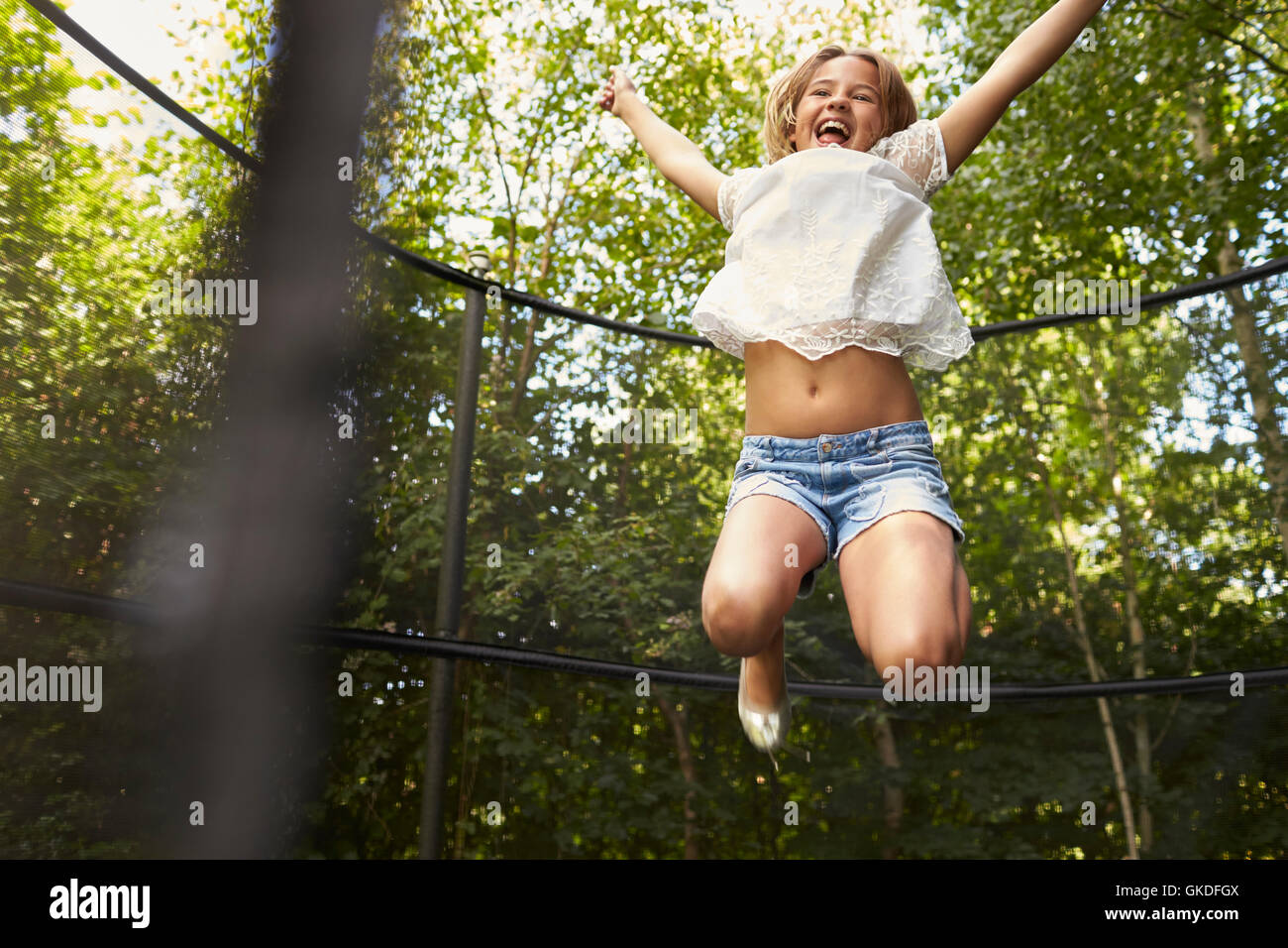 Ragazza divertirsi saltando sul trampolino in un giardino Foto Stock