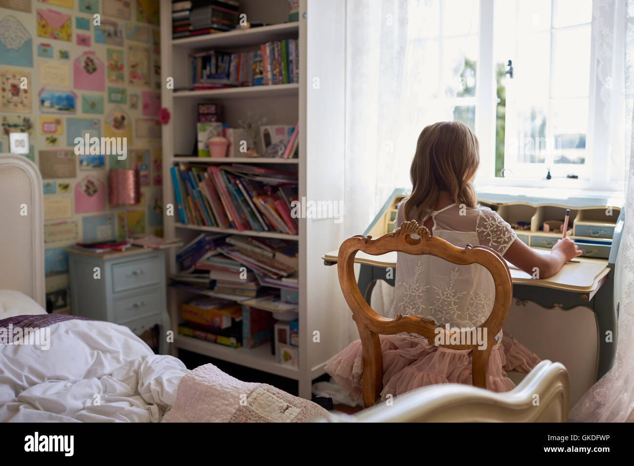 Vista posteriore della ragazza seduta alla scrivania e scrittura in camera da letto Foto Stock