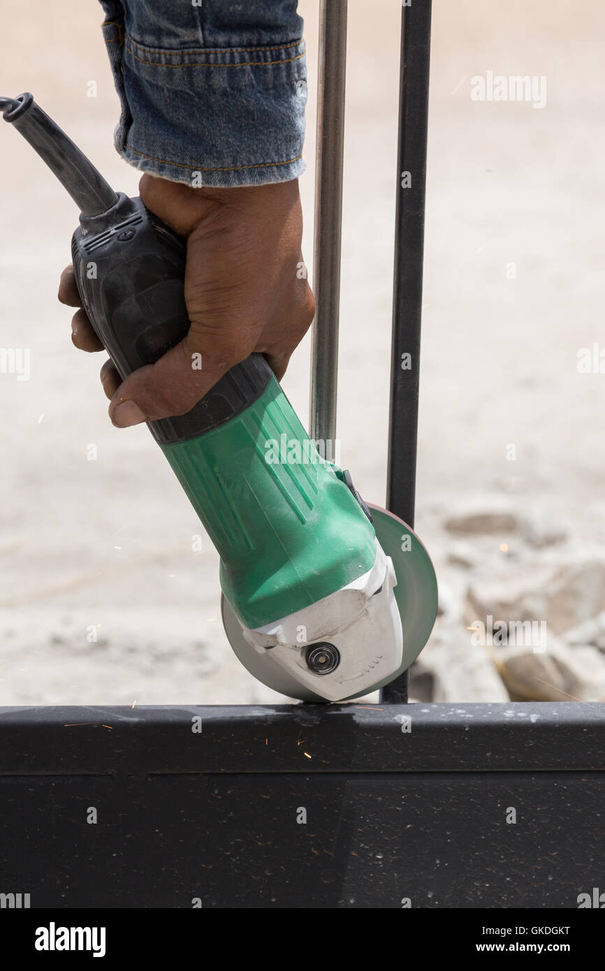 Mano del lavoratore utilizzando una smerigliatrice angolare per macinazione di telai di porte Foto Stock