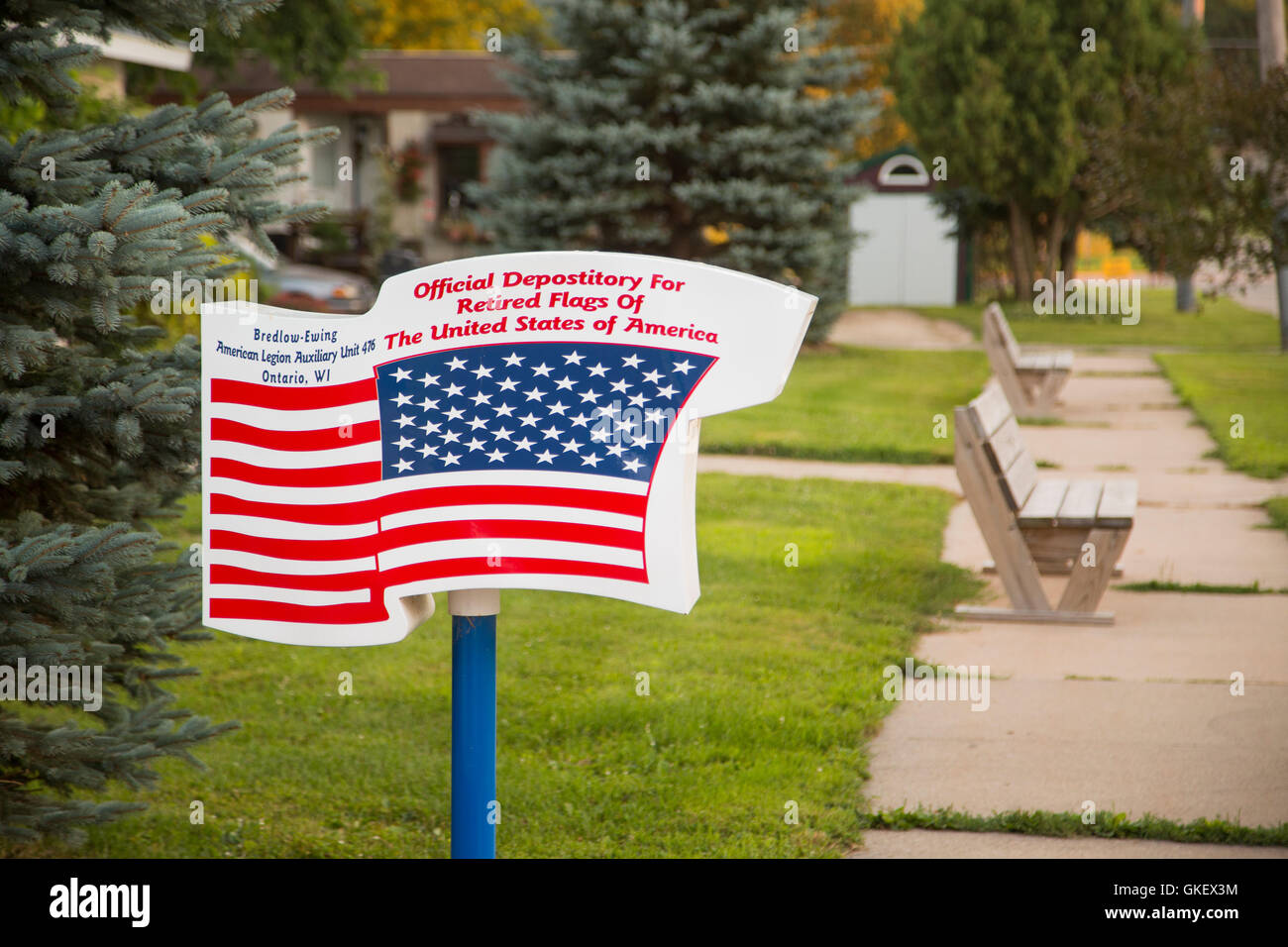 Un funzionario depositario per pensionati bandiere degli Stati Uniti d'America sorge nei pressi di un marciapiede di una piccola città in Wisconsin. Foto Stock