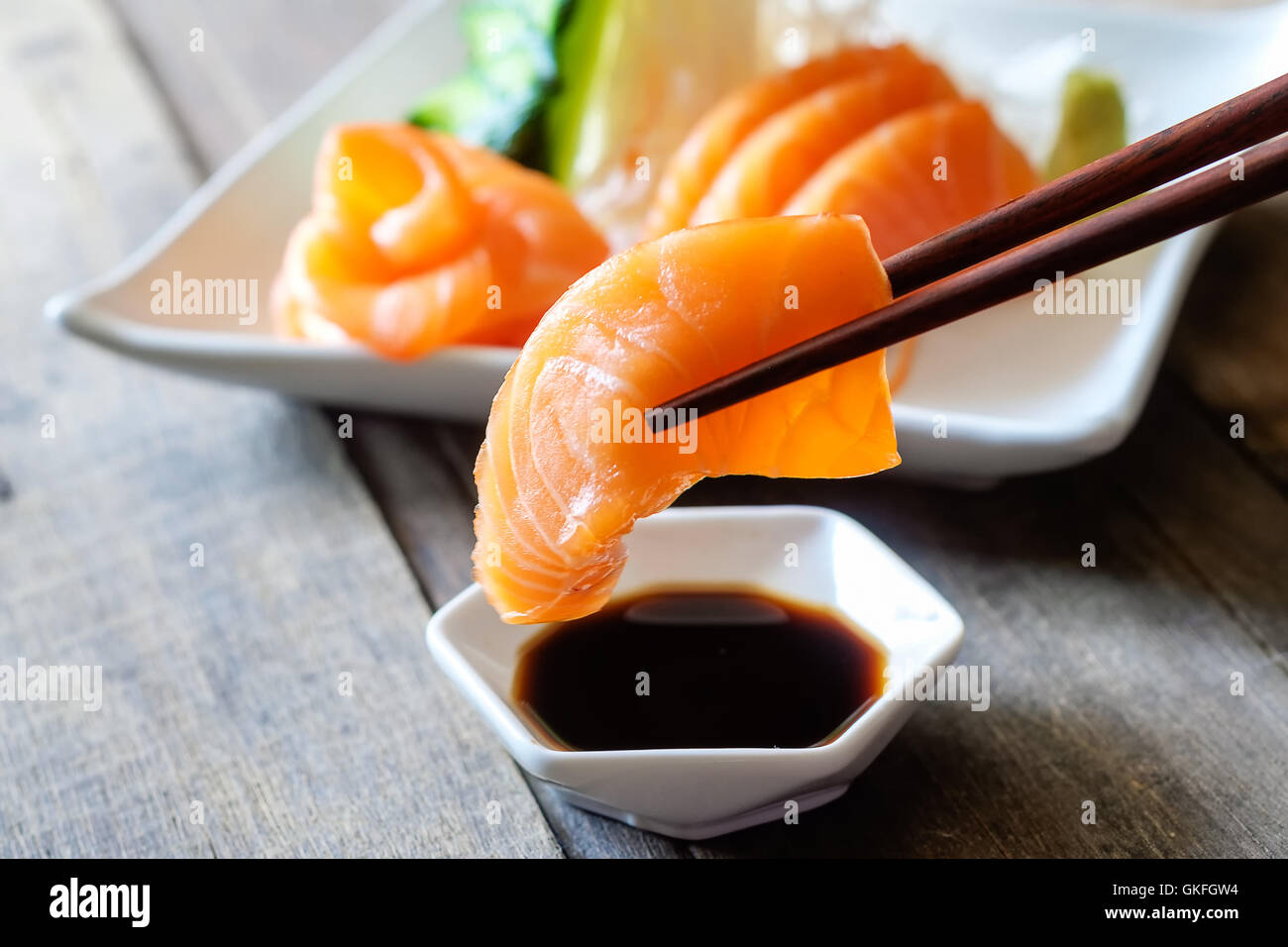Sashimi, salmone, il cibo giapponese bacchette e wasabi sulla tavola di legno Foto Stock