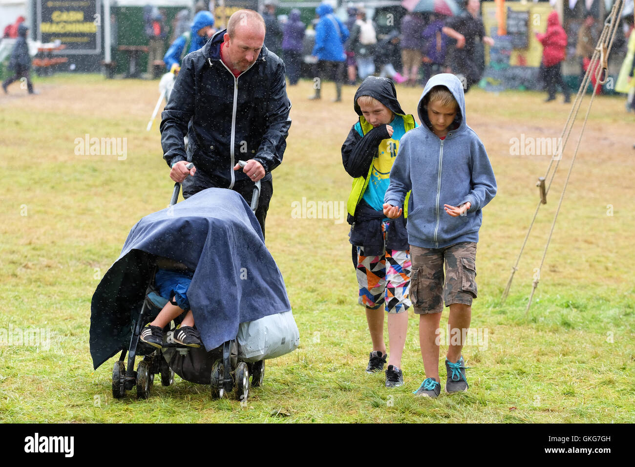 Green Man festival, Crickhowell, Galles - Agosto 2016 - La pioggia e la pioggia in più al Green Man festival con occasionali momenti di sole - Una famiglia fa del suo meglio per rimanere a secco durante un altro acquazzone pesante. Foto Stock