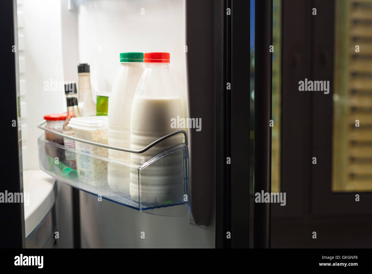 Aprire lo sportello del frigorifero con i prodotti lattiero-caseari nella notte Foto Stock