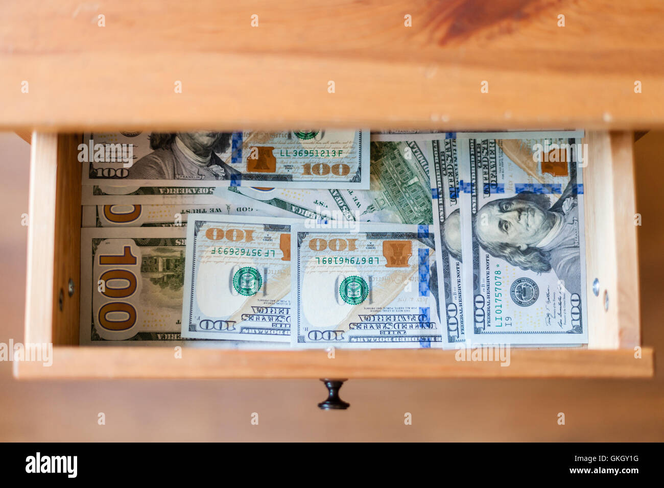 Vista dall'alto di molti un centinaio di dollari di banconote sul fondo di aprire il cassetto del comodino Foto Stock