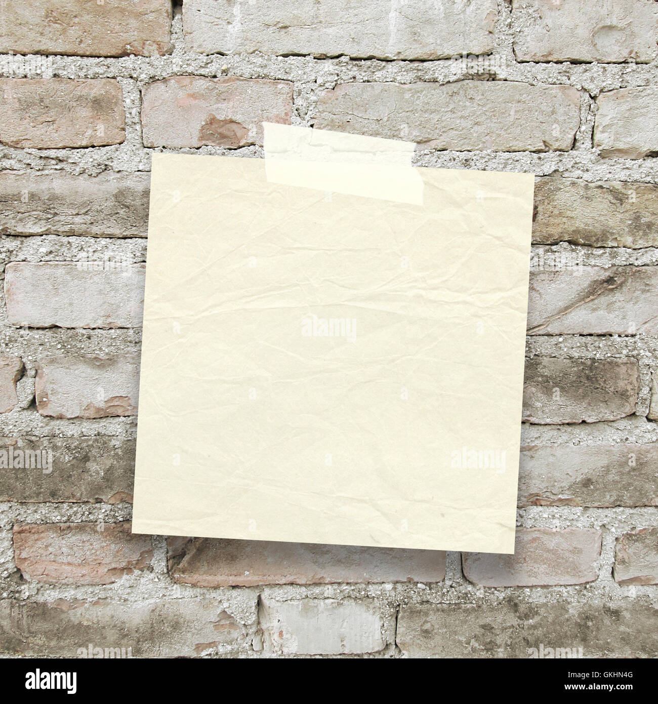 Close-up di un quadrato bianco il vecchio foglio di carta telaio con nastro adesivo sul vecchio muro di mattoni in background Foto Stock