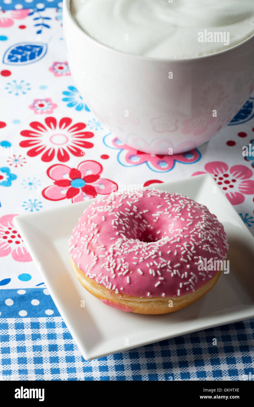 Ciambella di rosa e una tazza di cappuccino Foto Stock