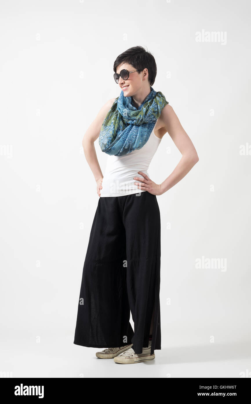 Capelli corti ragazza con occhiali da sole e scialle in posa con le mani  sui fianchi sopra grigio di sfondo per studio Foto stock - Alamy