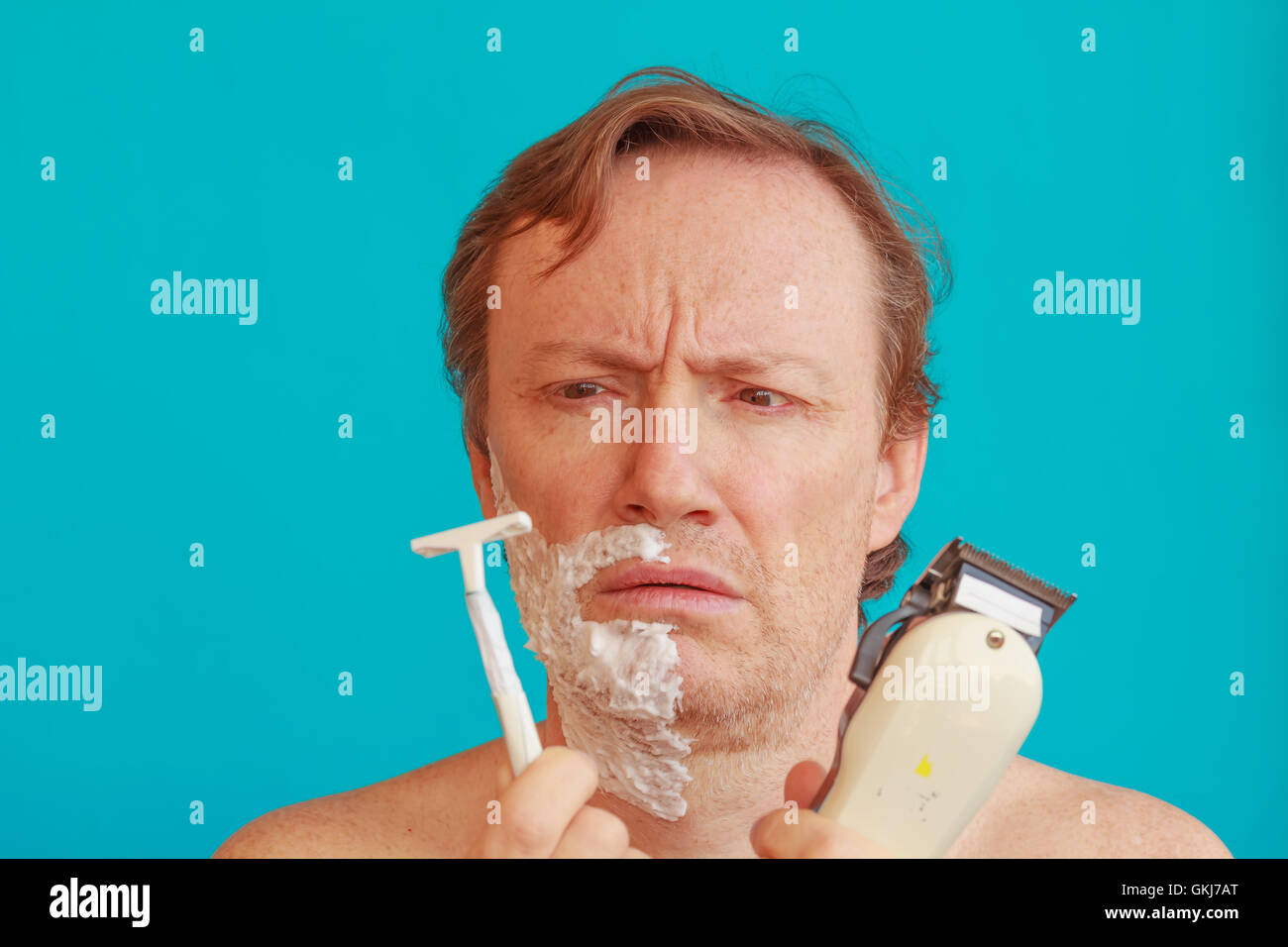 Un uomo per la rasatura deve scegliere tra il rasoio o un rasoio a lama Foto Stock