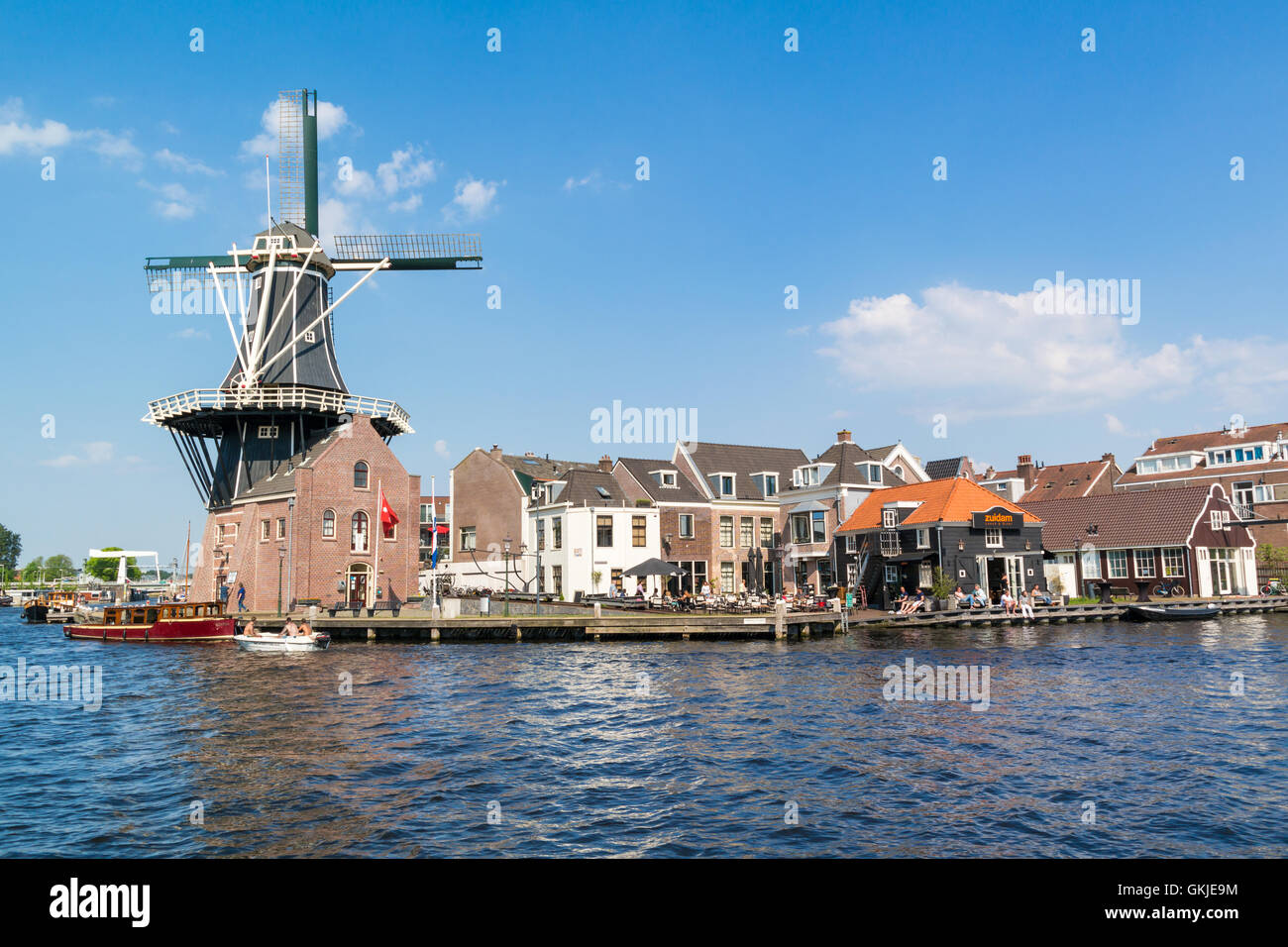 Barche, windmill Adriaan e persone su waterfront cafe accanto al fiume Spaarne in Haarlem, Paesi Bassi Foto Stock