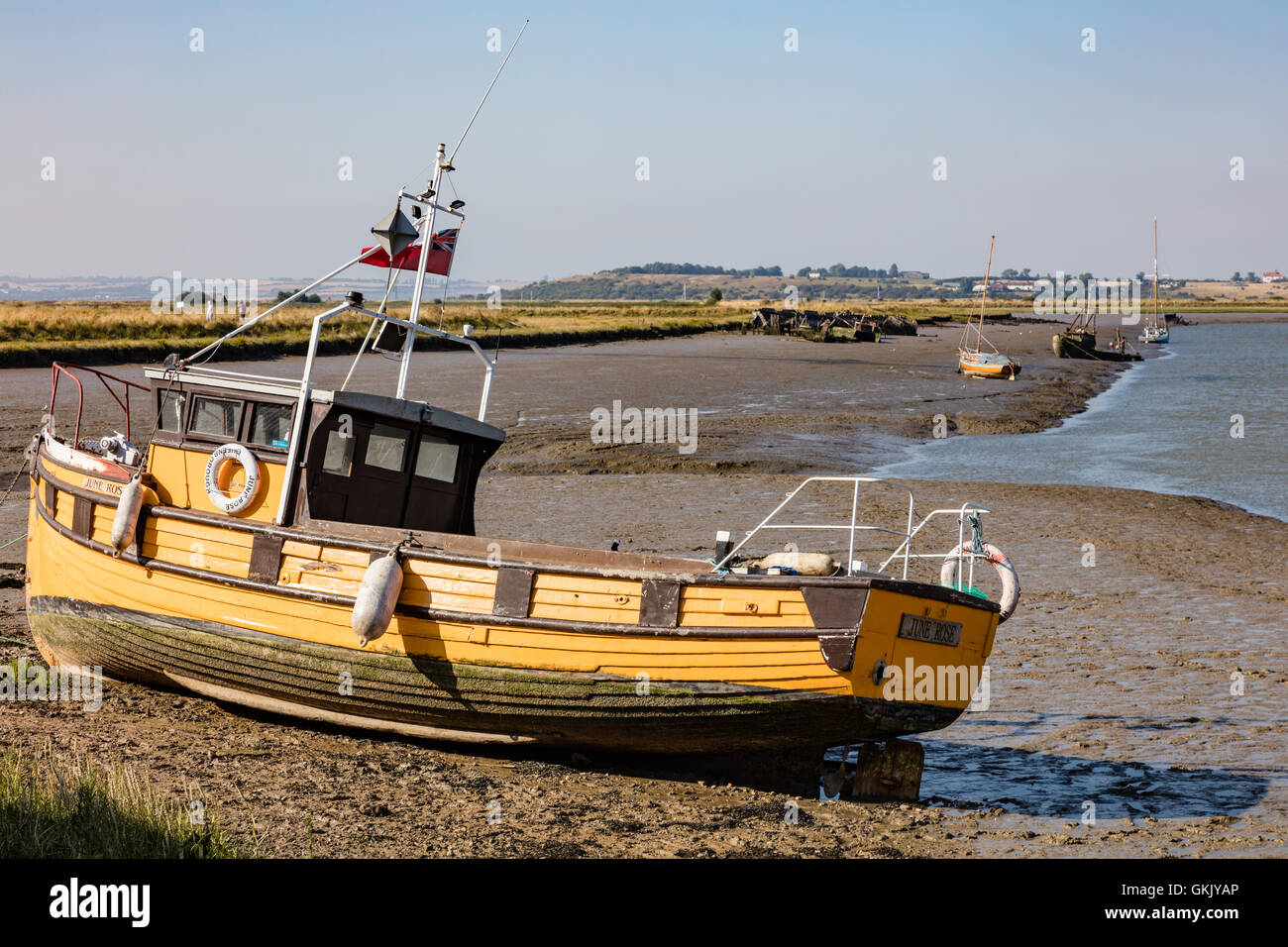 Piccola barca da pesca ormeggiate in corrispondenza della giunzione di Osono Creek e Faversham Creek, nel fango con la bassa marea, Faversham Kent, Regno Unito Foto Stock