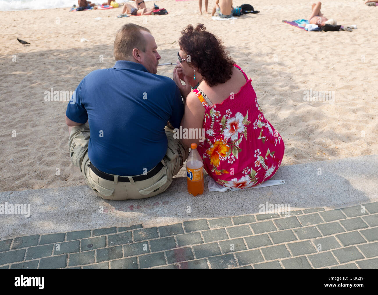 Western vacanzieri condividendo una sigaretta spiaggia di Pattaya Thailandia Foto Stock