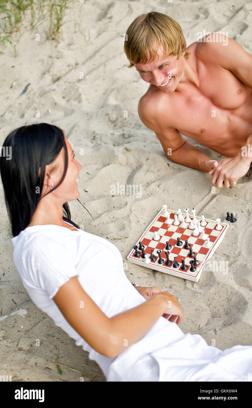 Coppia giovane giocando a scacchi sulla spiaggia Foto Stock