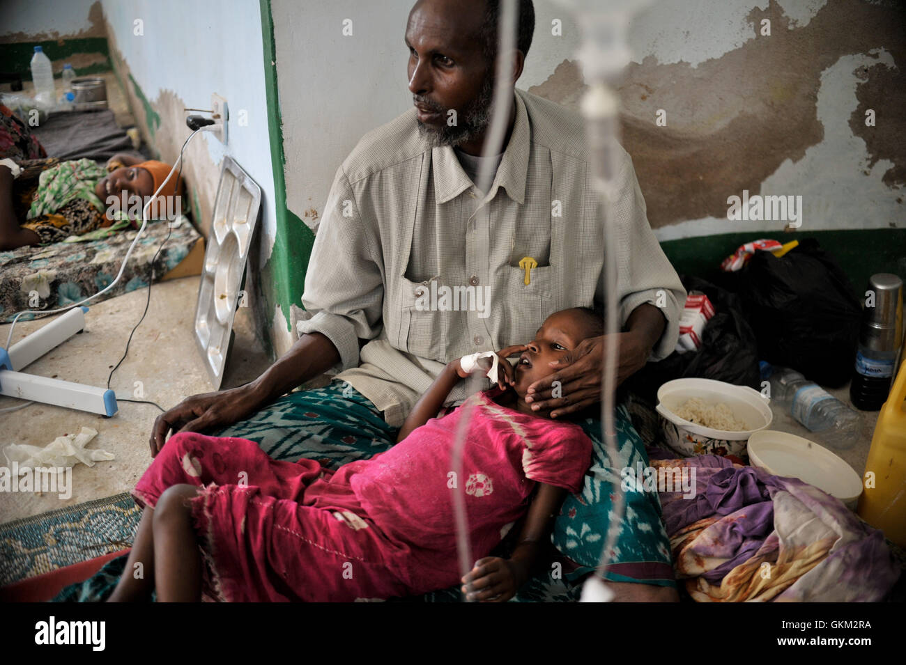 Un padre si prende cura di sua figlia in una clinica medica improvvisata a Belet Weyne, Somalia, il 30 marzo 2016. Una delegazione governativa indagò su un sospetto focolaio di colera, ma confermò che la diarrea acquosa acuta era responsabile della maggior parte dei ricoveri ospedalieri, non del colera. Foto Stock