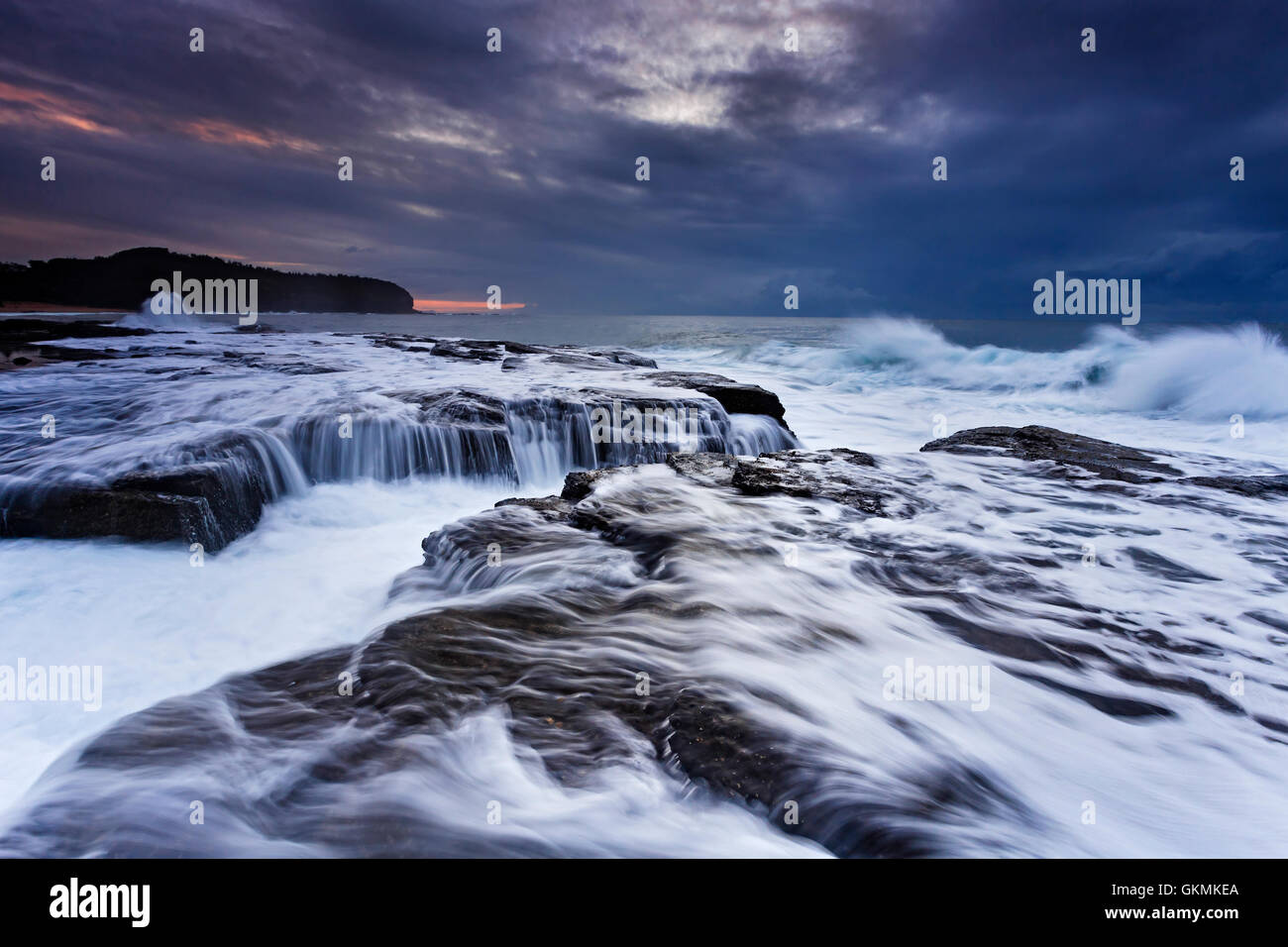 Forte onda di marea di minare le rocce di arenaria vicino Collaroy spiagge del nord di Sydney a sunrise. Meteo drammatico nasconde in aumento Foto Stock