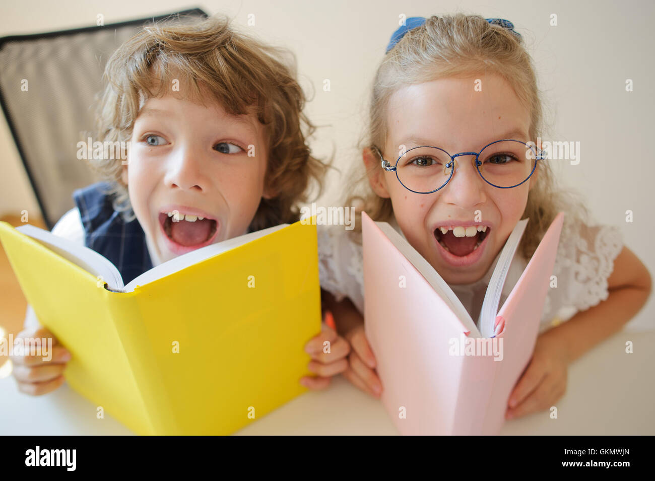 Due giovani classmate, un ragazzo e una ragazza, sono seduti allo stesso tavolo. I bambini imparano a scuola elementare. Nelle mani del studen Foto Stock