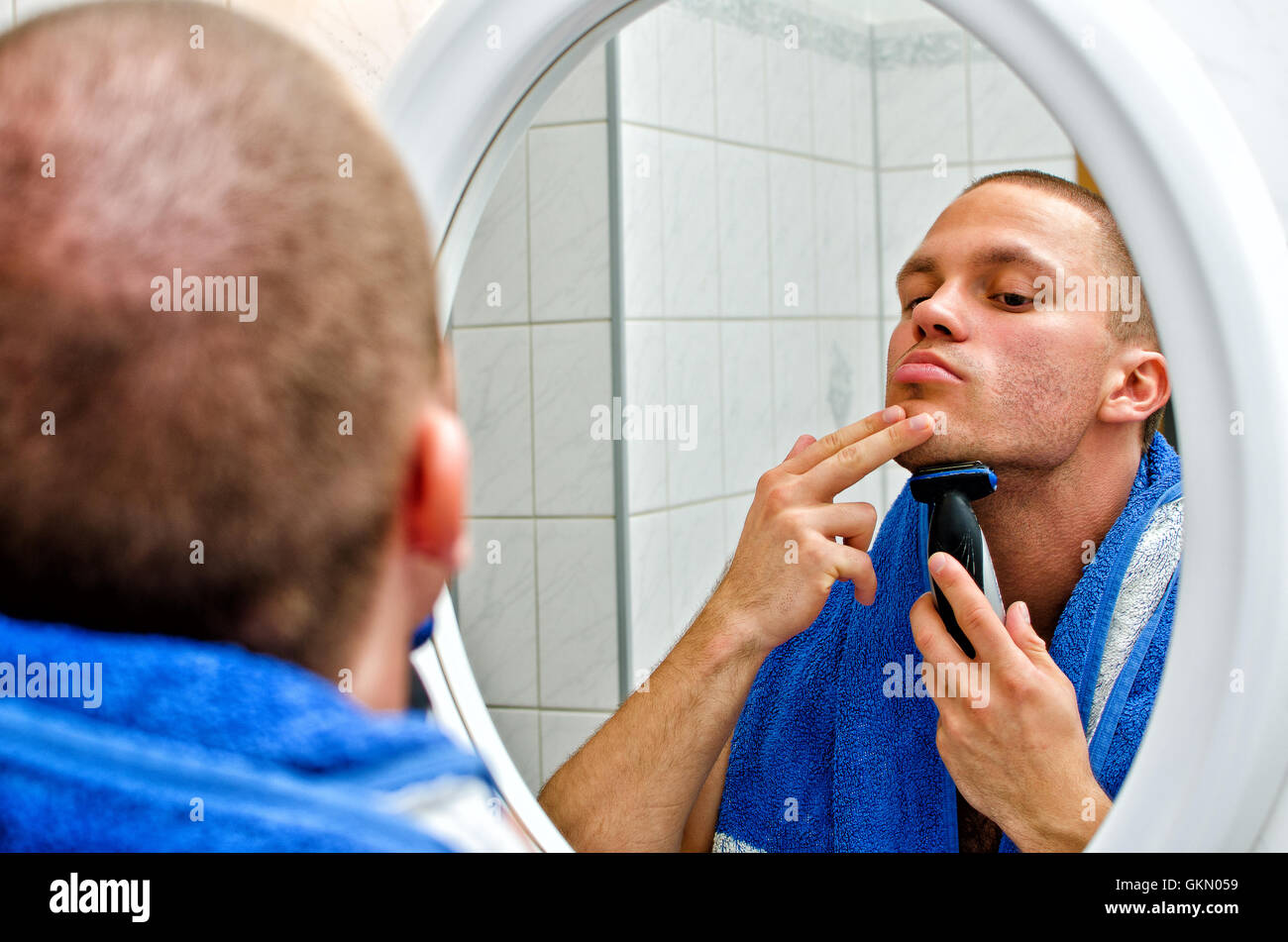 Maschio con rasatura di asciugamani in bagno di fronte allo specchio. Foto Stock