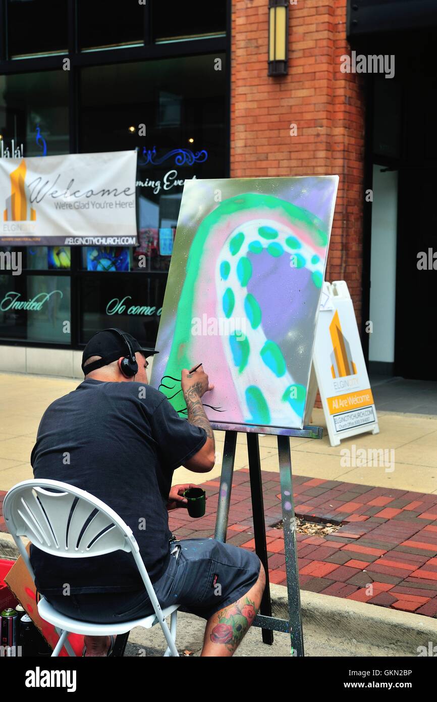 Un artista che lavora sulla sua ultima creazione durante un weekend di street art fair nel centro cittadino di Elgin, Illinois, Stati Uniti d'America. Foto Stock