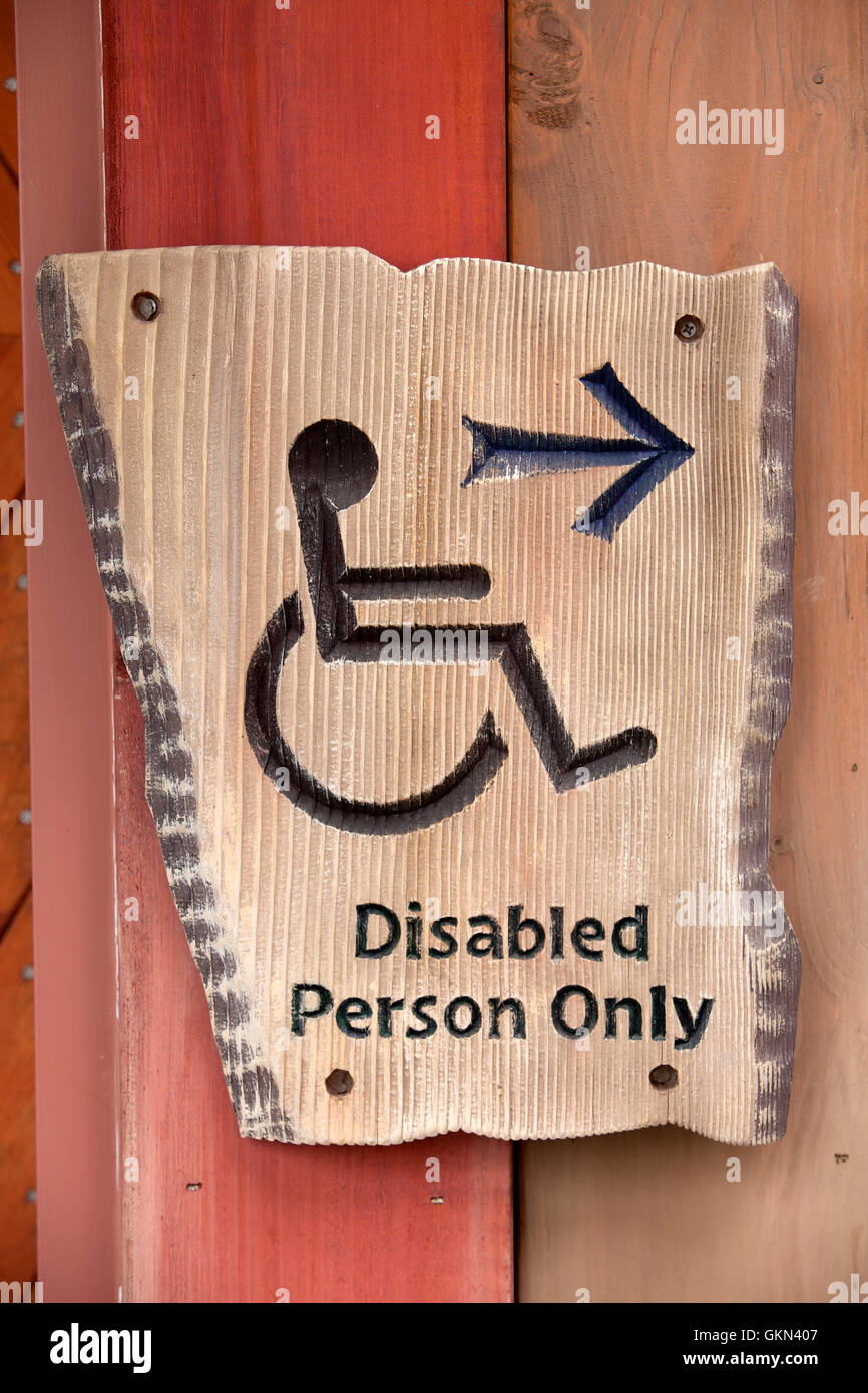 Un segno di portatori di handicap su parete in legno Foto Stock