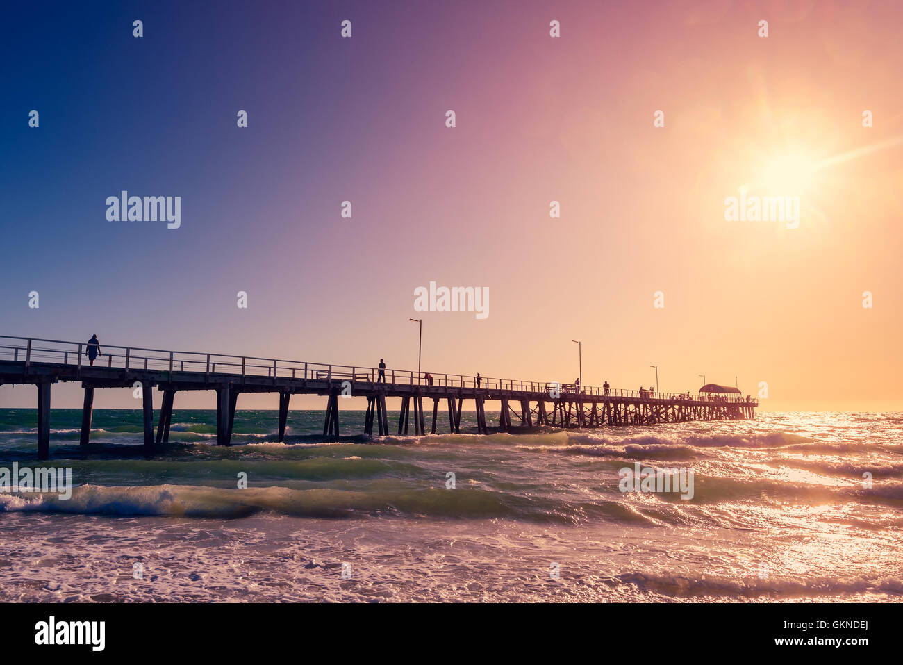 La gente camminare lungo il Henley Beach Jetty di una calda serata di sole. Color-tonificante applicato Foto Stock