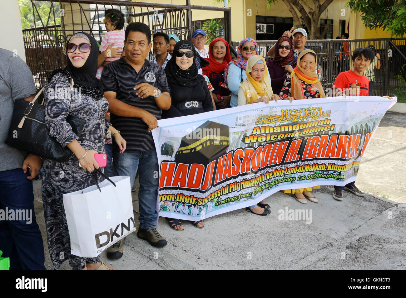 Parenti con una targhetta salutare rimpatriati dal loro pellegrinaggio alla Mecca all aeroporto di Cotabato, sull isola di Mindanao, Filippine Foto Stock
