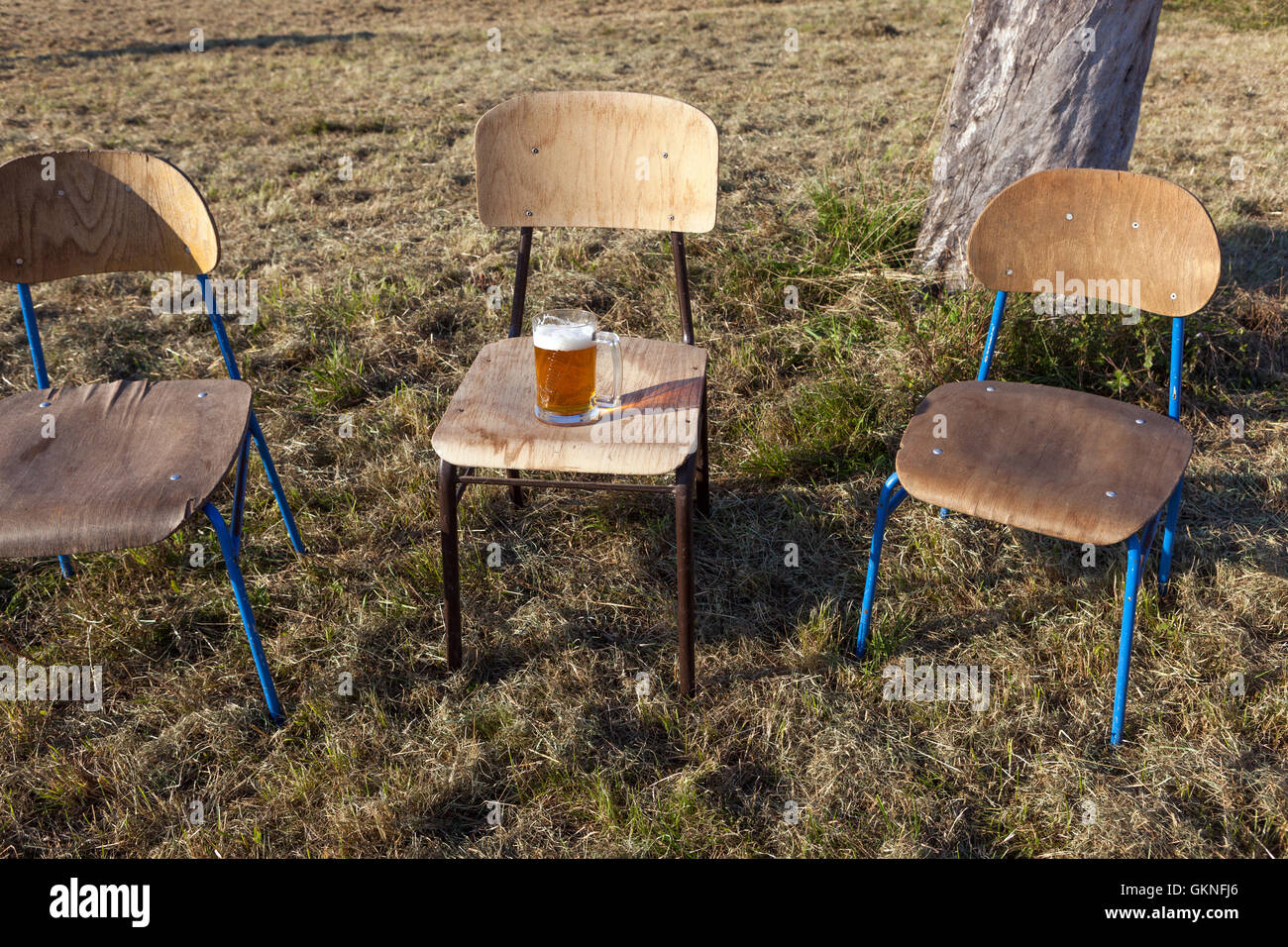 Birra alla spina fresca messa su una vecchia sedia di legno, tre sedie Foto Stock