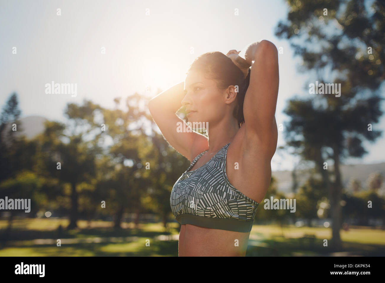 Immagine ravvicinata di modello di fitness facendo stretching allenamento presso il parco. Determinata giovane donna indossa sports bar esercitando su una s Foto Stock