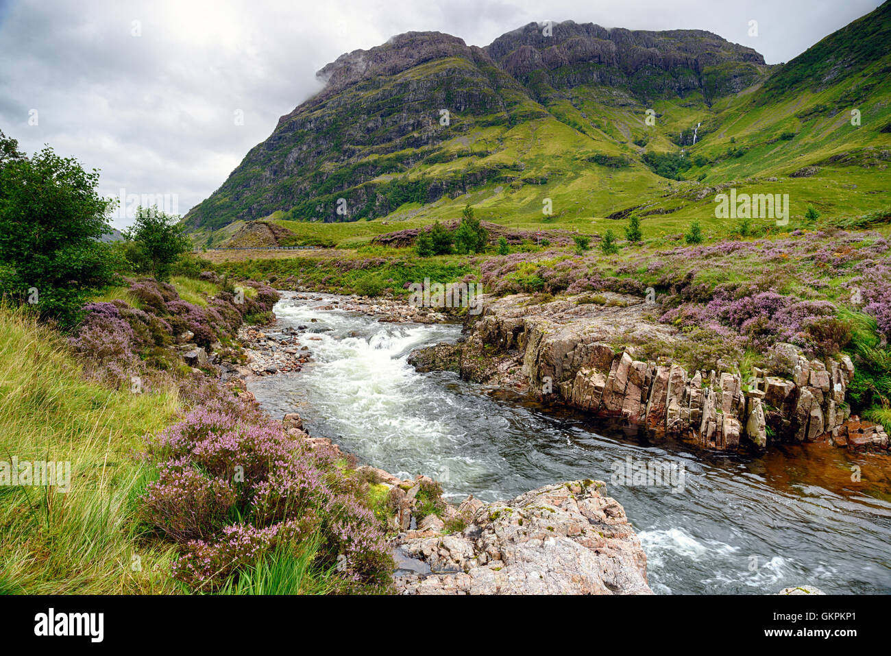 Il fiume Coe cascading attraverso la valle al di sotto delle montagne a Glencoe nelle Highlands scozzesi Foto Stock
