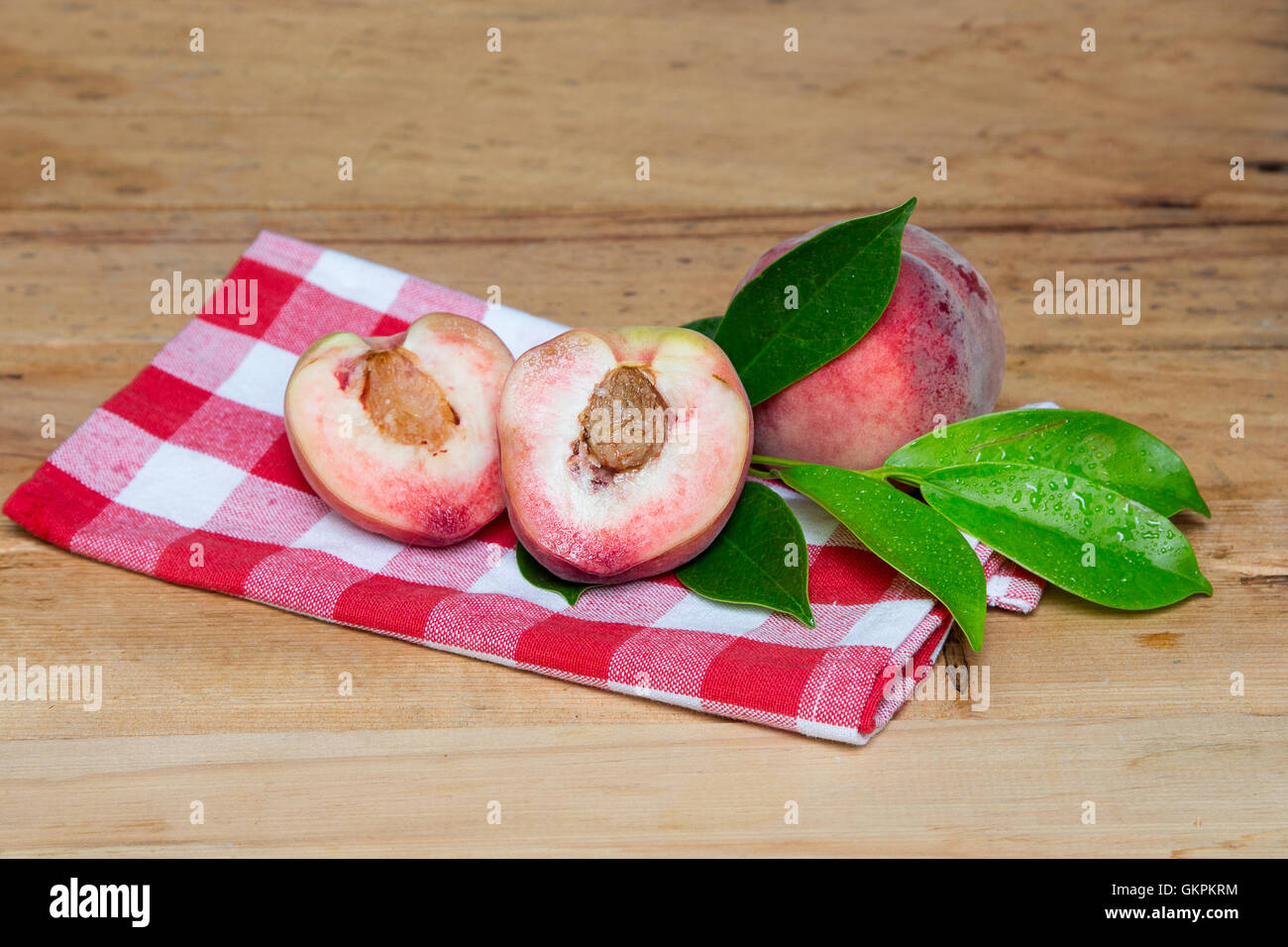Mature di pesche fresche isolate su uno sfondo di legno. Peschi in un taglio Foto Stock