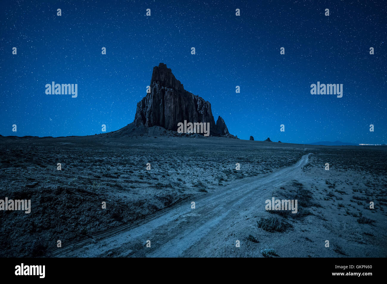 Cielo notturno con molte stelle sopra Shiprock e una strada sterrata Foto Stock