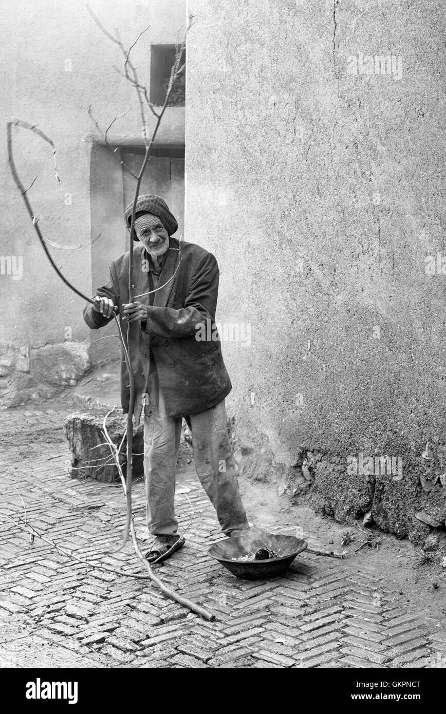 Un uomo Abyanaki costruire un fuoco per cuocere nel borgo antico di Abyaneh, Iran. Foto Stock