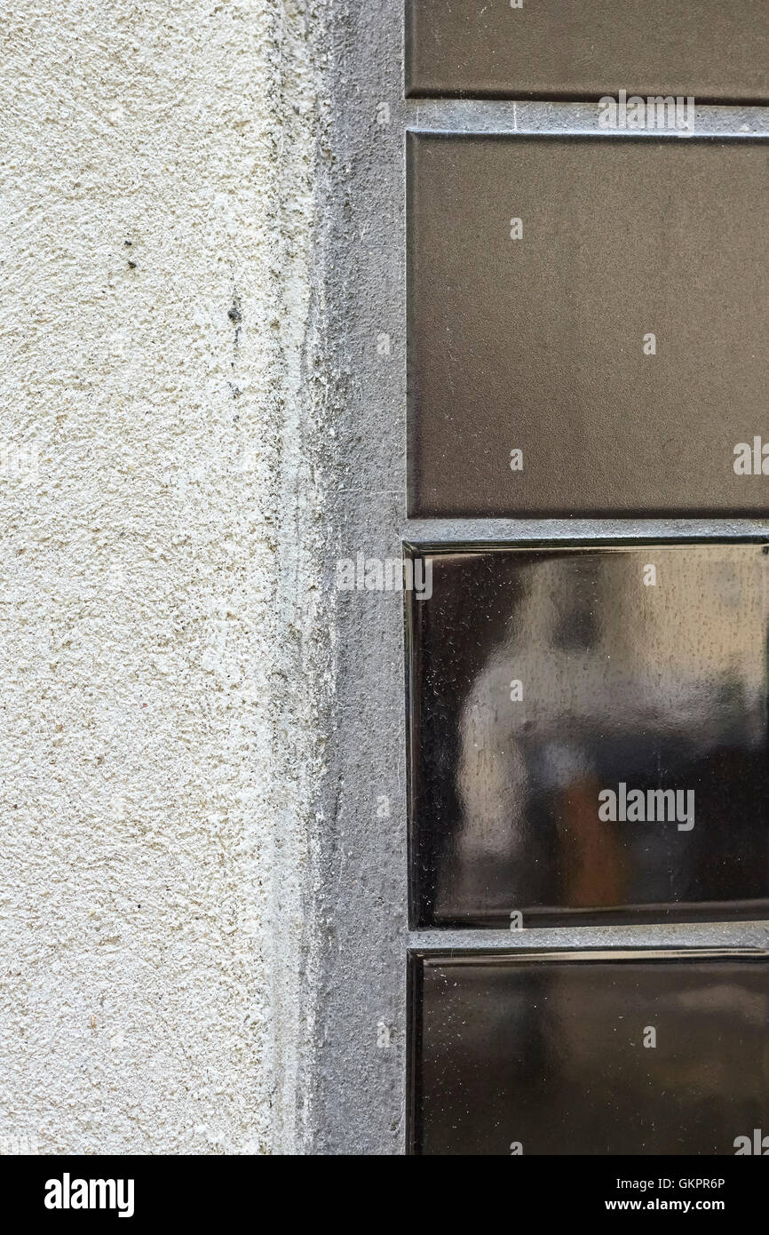 Piastrelle scure su porosa parete grigia Foto Stock