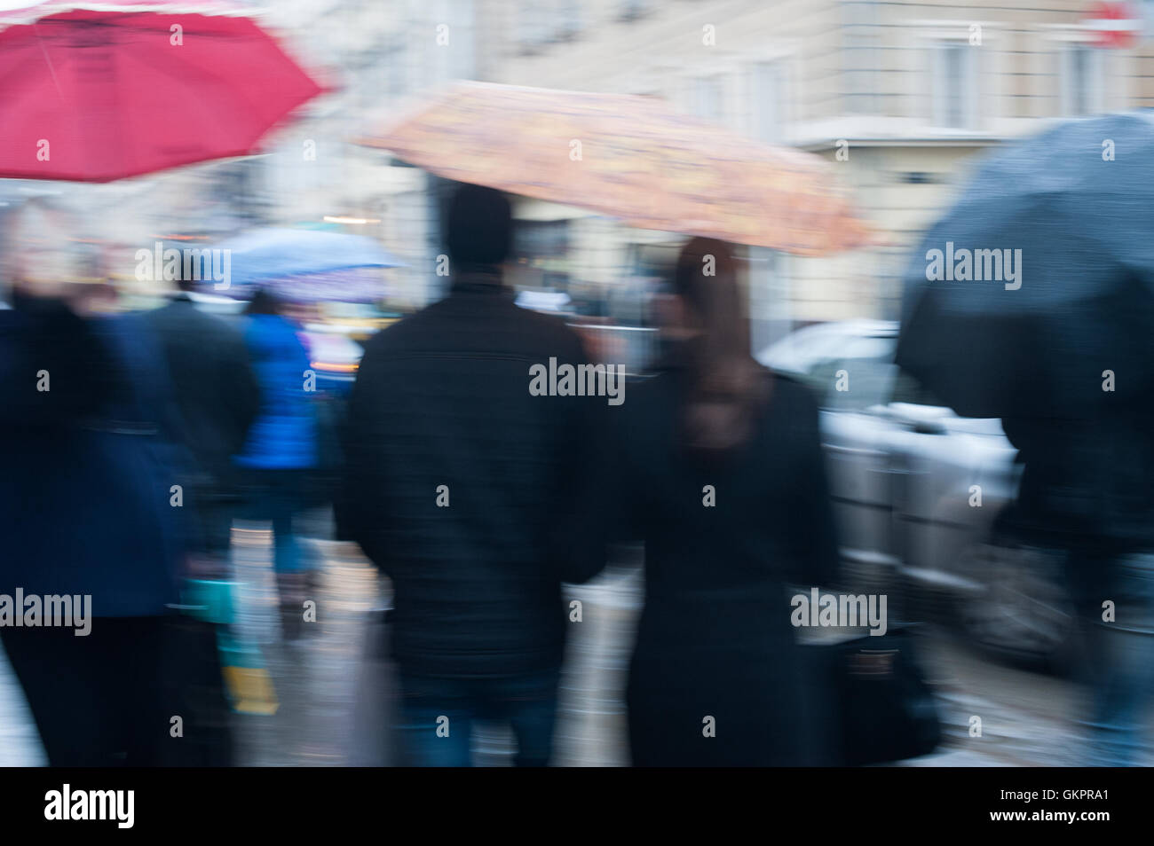 Una folla di gente che attraversando via sul giorno di pioggia nella città Foto Stock
