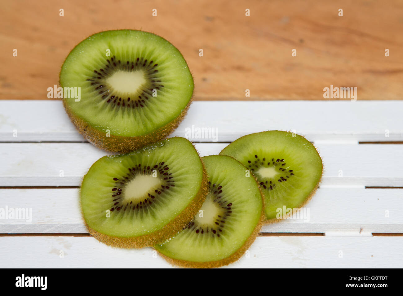 Fette di kiwi verde su uno sfondo di legno. Foto Stock
