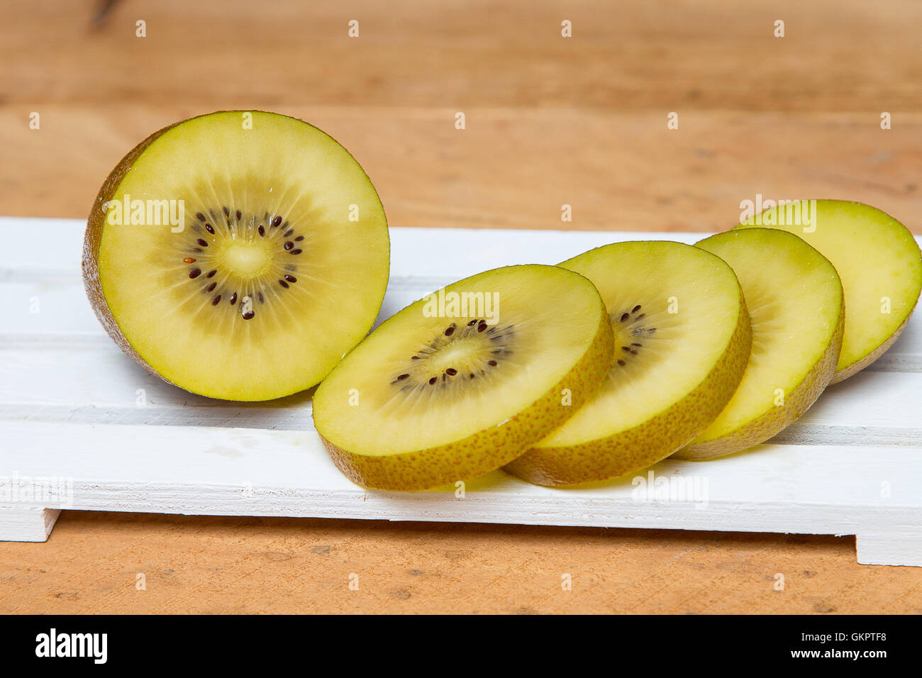 Close-up. Tagliate a fette di kiwi giallo su uno sfondo di legno. . Foto Stock