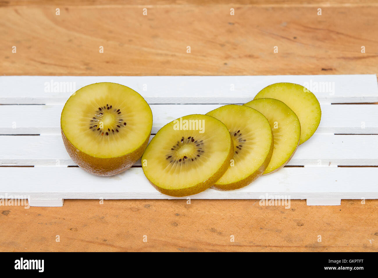 Kiwi giallo fetta su uno sfondo di legno Foto Stock
