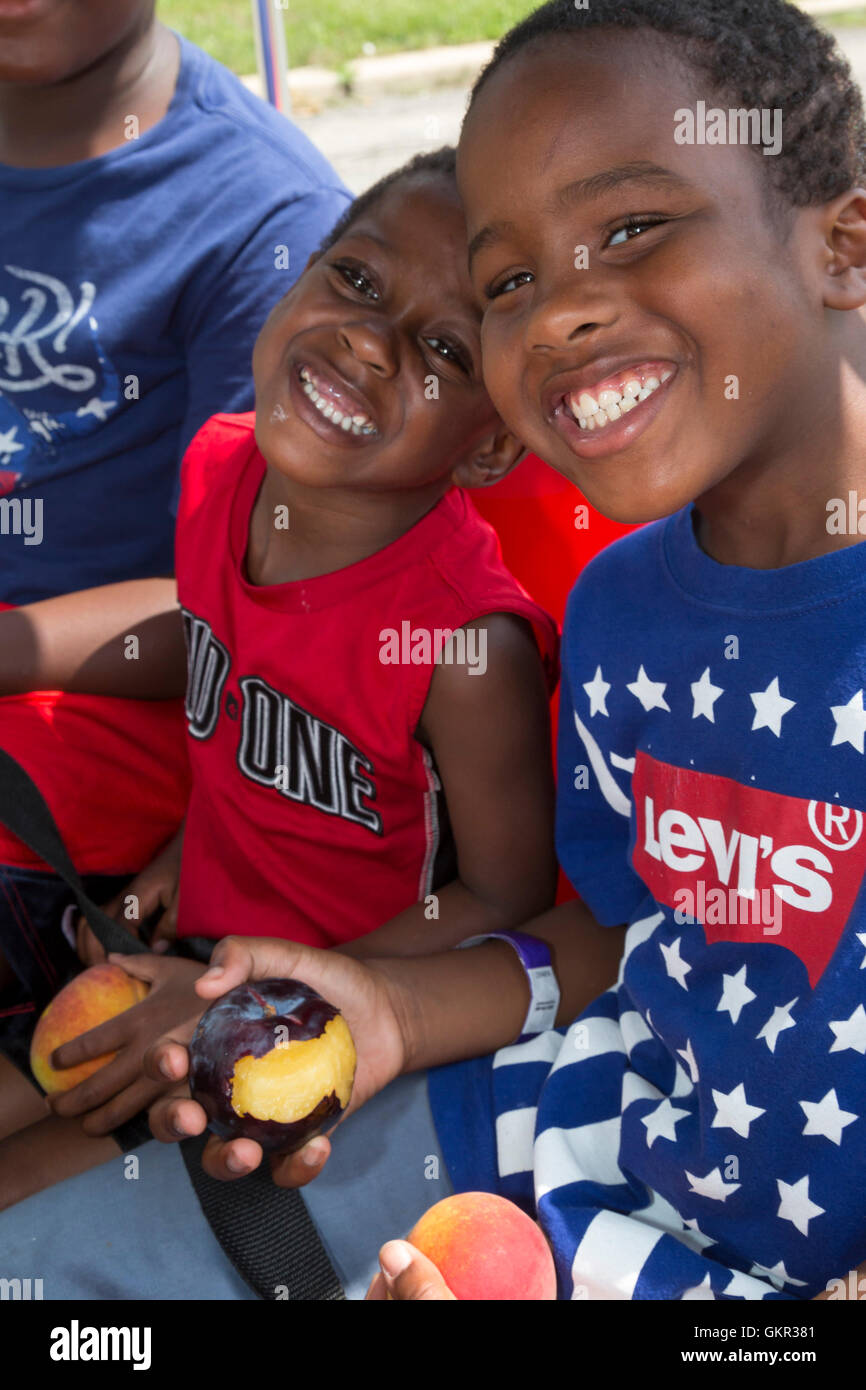 Detroit, Michigan - Bambini con frutta fresca distribuita durante un estate street fair detenute da un gruppo di quartiere. Foto Stock