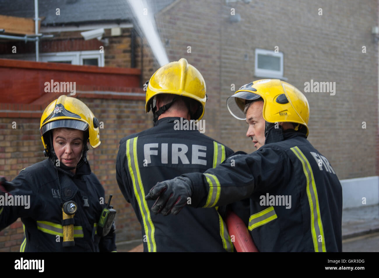 Tre vigili del fuoco di Londra operando una altezza piattaforma alla scena di un incendio a Londra Foto Stock