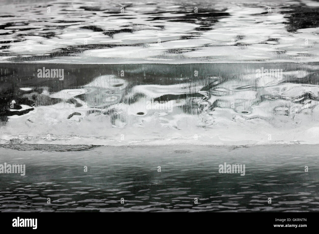 Uno spesso strato di ghiaccio incrinato con round bolle di aria abstract Foto Stock